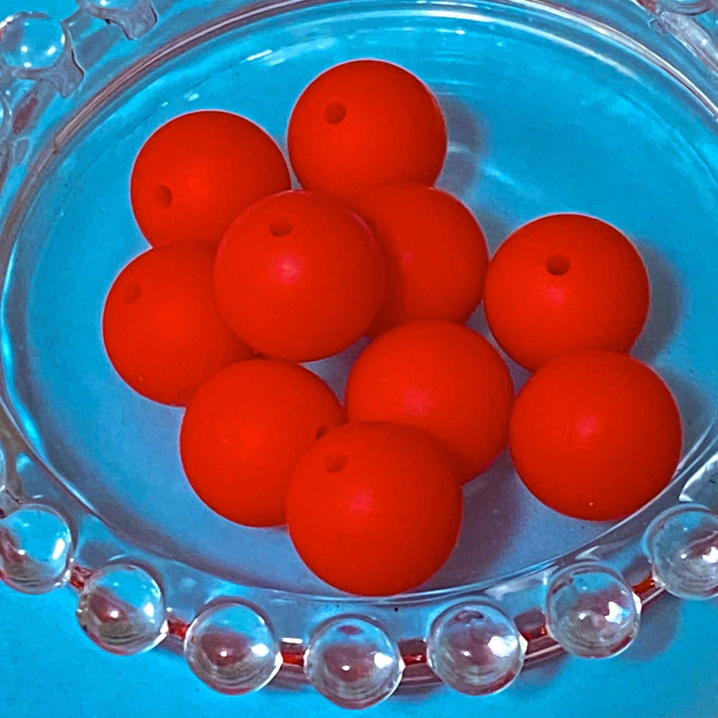 Red round 16mm silicone beads on a clear glass plate
