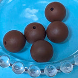 Brown round 16mm silicone beads on a blue glass plate with clear beads at the bottom.