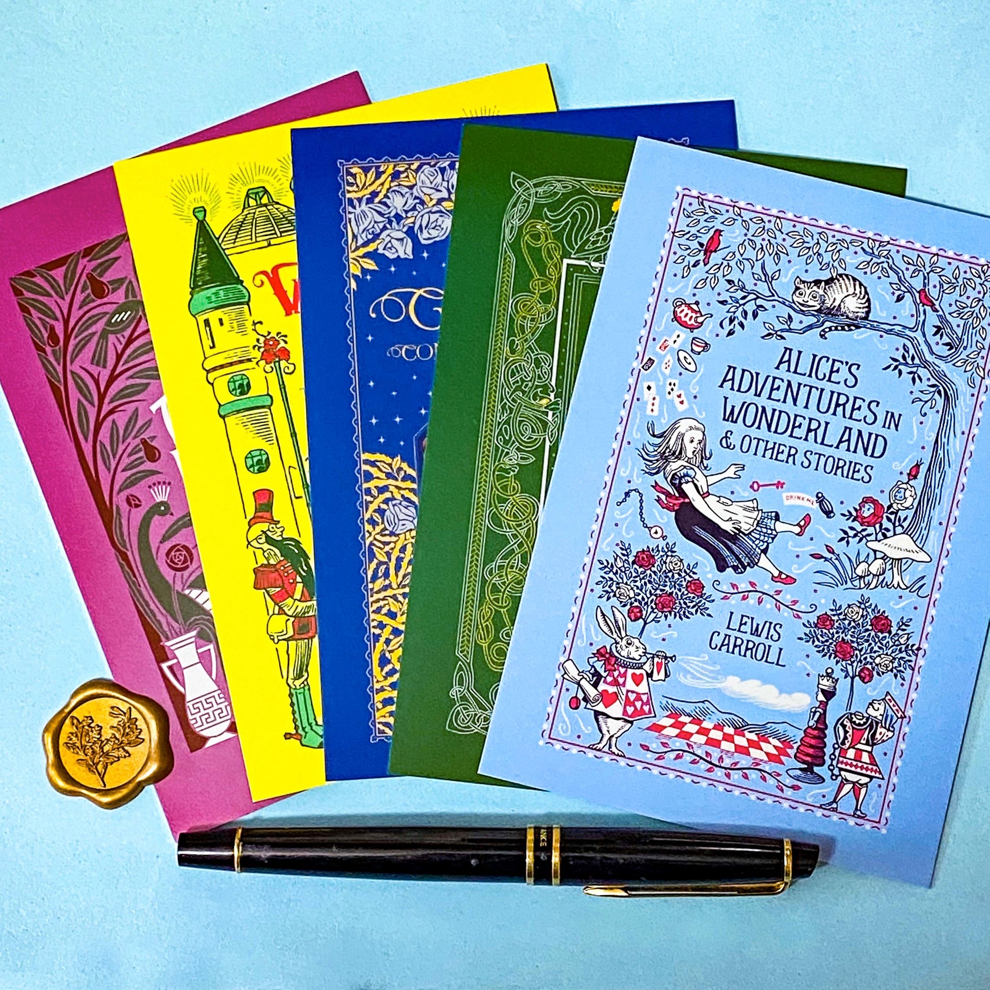 set of 5 vintage literary postcards featuring fairytale book covers including Alice in Wonderland, Wizard of Oz and Grimm Fairy Stories on a blue Background