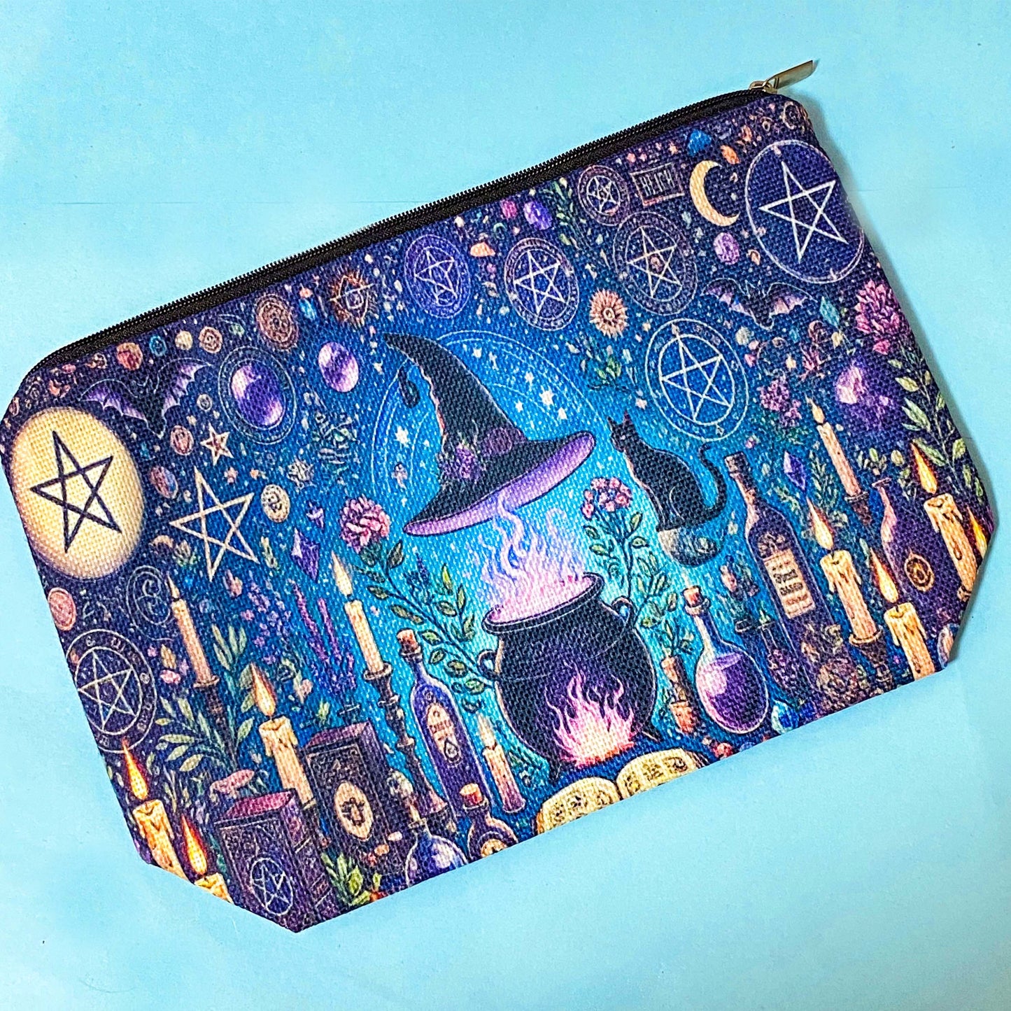 witchy pouch with purple and blue celestial magical design including cauldron, symbols, candles and books.