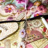 vintage floral letterbox gift set with large flower pouch, pearly white metal pen, daisy tassel acrylic bookmark, floral postcards and vintage decorative journaling stickers on pink background. UK cute gifts and stationery sets.