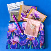 botanical iris letterbox gift set with waterproof floral pouch, purple metal pen, enamel iris brooch in pink velvet bag, clear floral stickers and hummingbird greetings cards. purple, deep jewel blue, lilac and magenta coloured flowers.