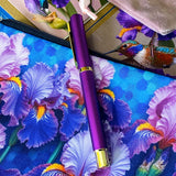 botanical iris letterbox gift set with waterproof floral pouch, purple metal pen, enamel iris brooch in pink velvet bag, clear floral stickers and hummingbird greetings cards. purple, deep jewel blue, lilac and magenta coloured flowers.