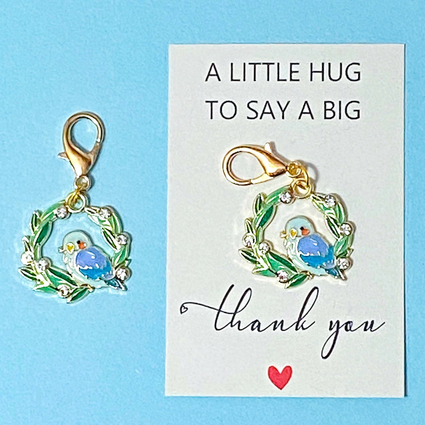 Two bird-themed charms on a card with 'A little hug to say a big thank you' text on a blue background.
