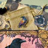 gothic raven themed letterbox gift set with ornate crow fabric pouch, gold metal pen, enamel raven pin brooch, vintage metal bookmark, dark paper stickers and scrapbook papers. Uk gift shop with mystical and witchy gifts.