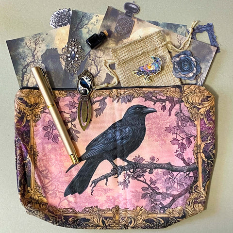 gothic raven themed letterbox gift set with ornate crow fabric pouch, gold metal pen, enamel raven pin brooch, vintage metal bookmark, dark paper stickers and scrapbook papers. Uk gift shop with mystical and witchy gifts.