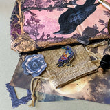 gothic raven themed letterbox gift set with ornate crow fabric pouch, gold metal pen, enamel raven pin brooch, vintage metal bookmark, dark paper stickers and scrapbook papers. Uk gift shop with mystical and witchy gifts.