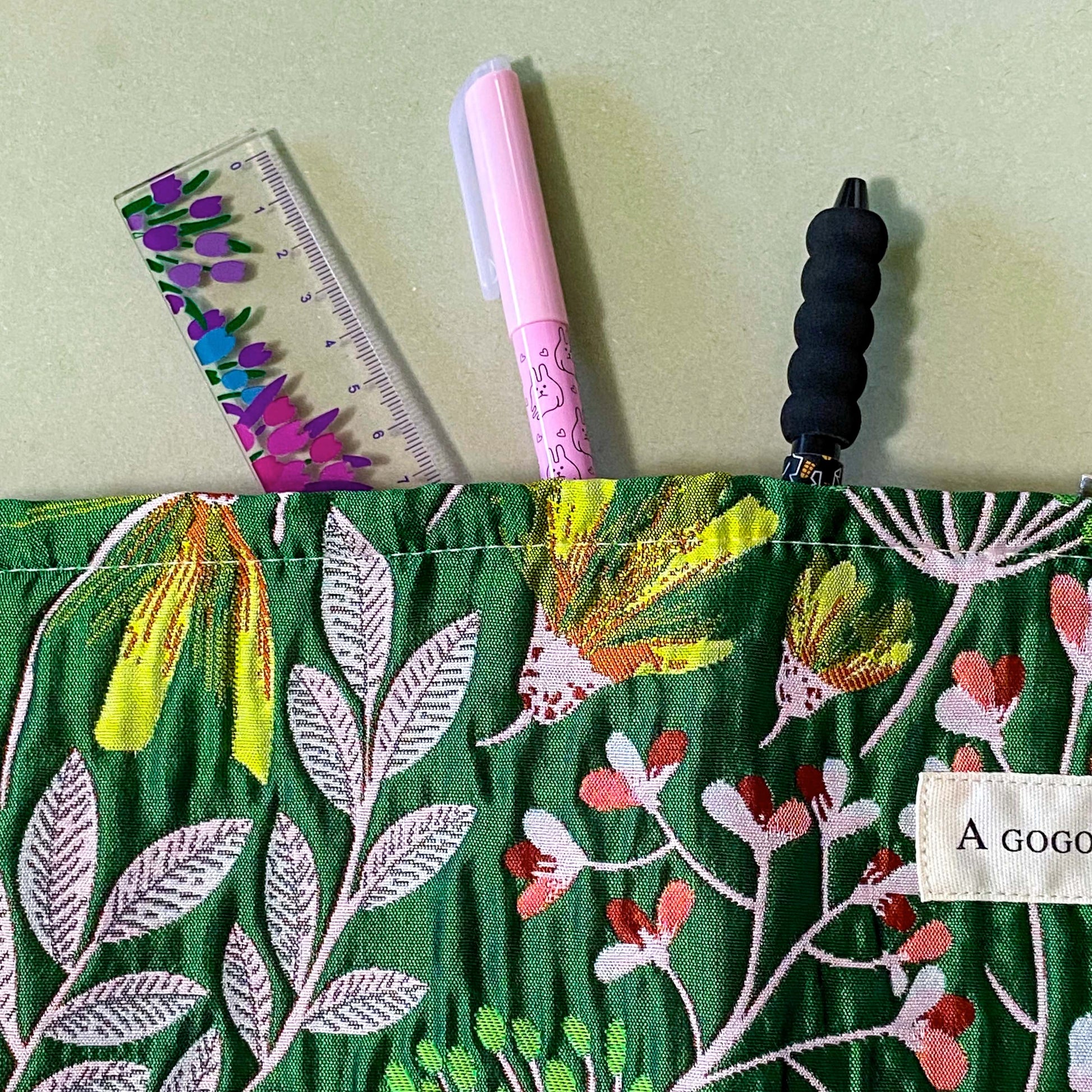 emerald conservatory tapestry pouch featuring a woven satin botanical design in emerald green, coral pink and cream with concealed zip fastening and cream lined interior. Uk luxury letterbox gifts shop. 