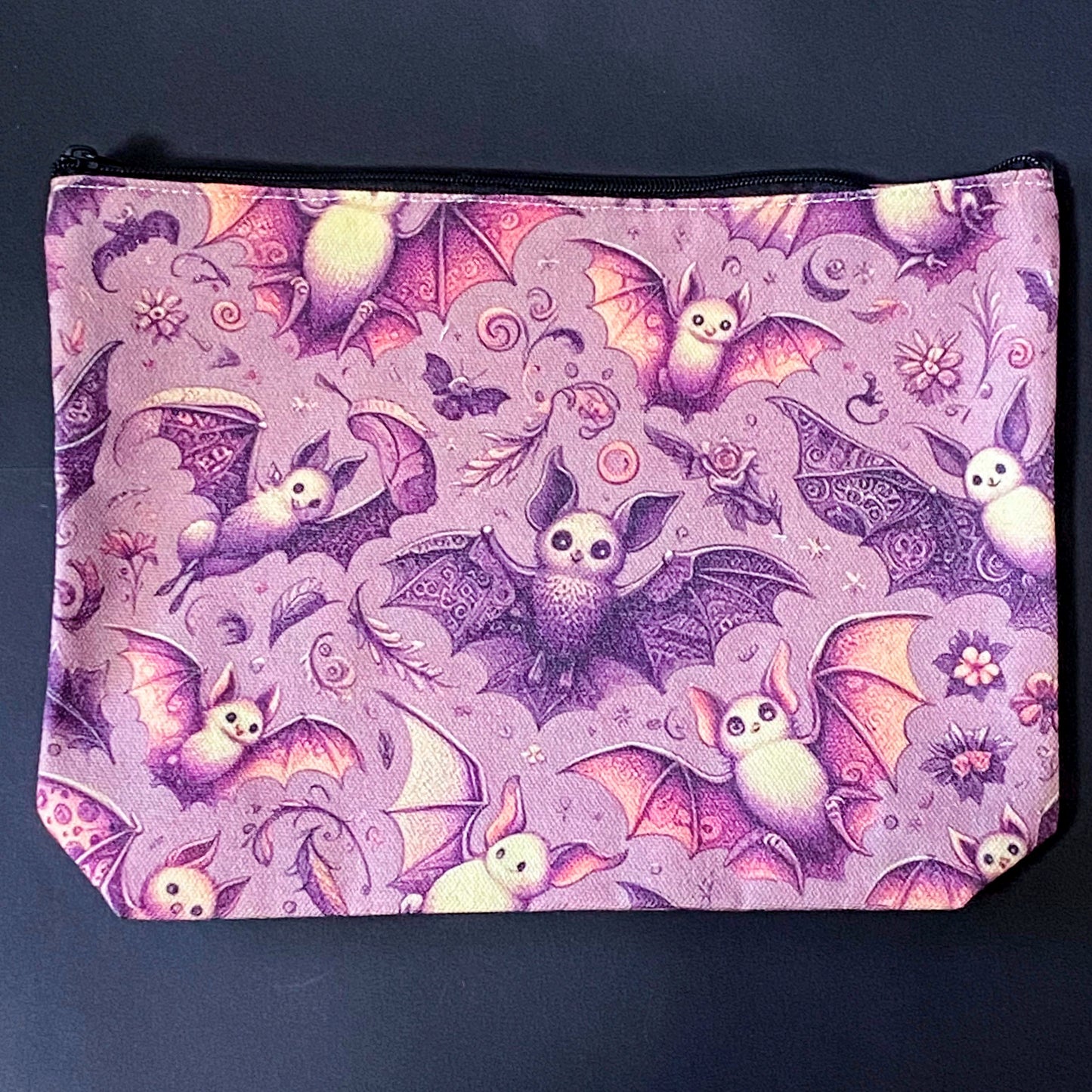 rosewing bats fabric zip pouch featuring whimsical pink and plum purple bats amongst flowers and feathers and moonlit details on a blush pink background. uk cosmetic bags from letterbox gift shop.