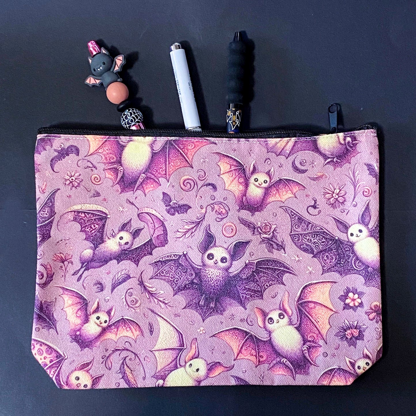 rosewing bats fabric zip pouch featuring whimsical pink and plum purple bats amongst flowers and feathers and moonlit details on a blush pink background. uk cosmetic bags from letterbox gift shop.