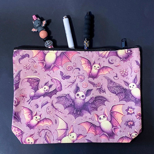 rosewing bats fabric zip pouch featuring whimsical pink and plum purple bats amongst flowers and feathers and moonlit details on a blush pink background. uk cosmetic bags from letterbox gift shop.
