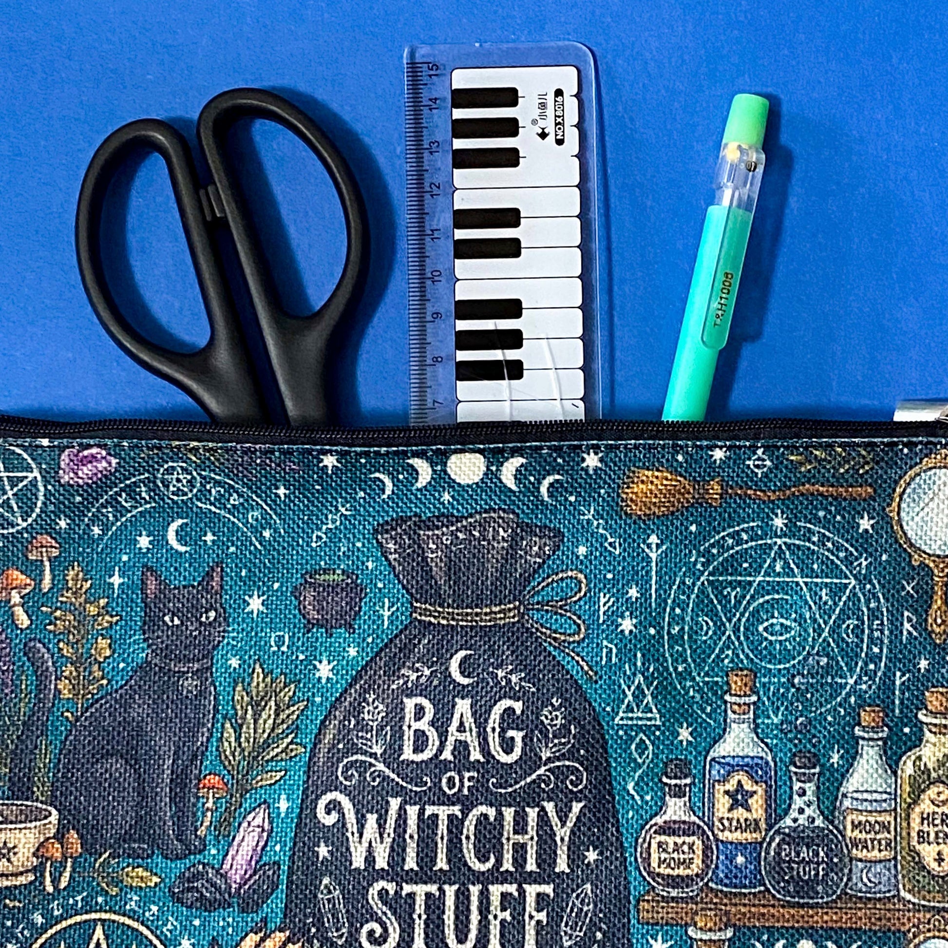black cat apothecary zip pouch featuring witchy illustrations including a black cat potion bottles, crystals, herbs and moon phases. Teal and black fabric cosmetic bag. 