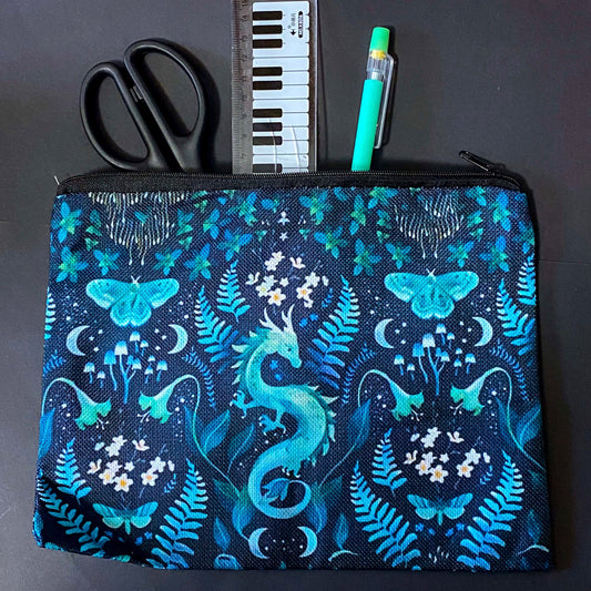 twilight fern dragon fabric zip pouch featuring a turquoise dragon surrounded by ferns, butterflies, flowers, mushrooms and crescent moons on a black background. turquoise, teal and mint green cosmetic bag. 