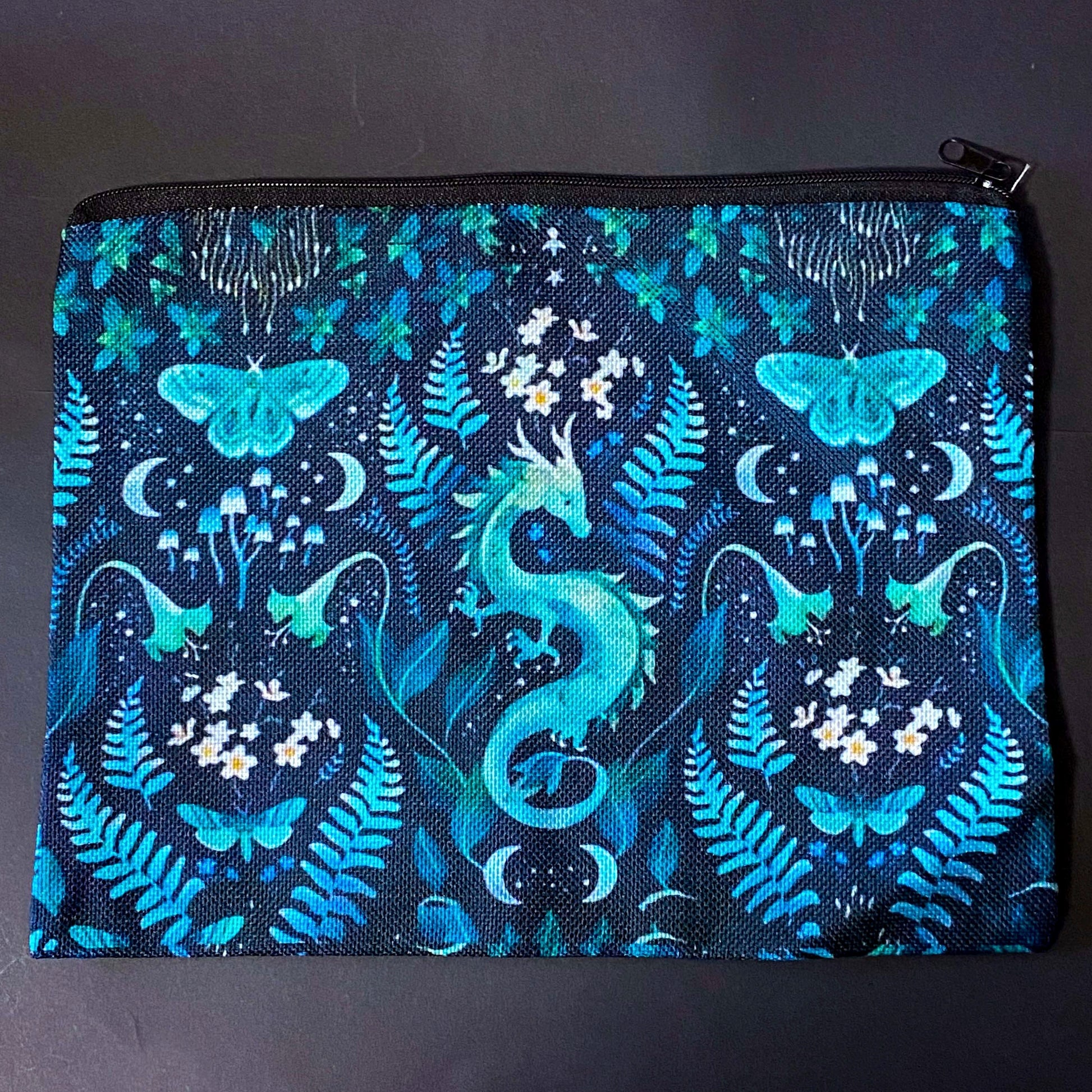 twilight fern dragon fabric zip pouch featuring a turquoise dragon surrounded by ferns, butterflies, flowers, mushrooms and crescent moons on a black background. turquoise, teal and mint green cosmetic bag. 
