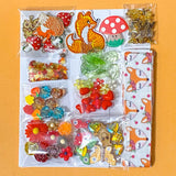 autumn fox craft bundle with grosgrain ribbon, beads, enamel charms, sequins and buttons in a cellophane pack on an orange background