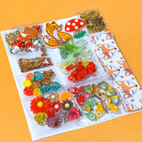 autumn fox craft bundle with grosgrain ribbon, beads, enamel charms, sequins and buttons in a cellophane pack on an orange background