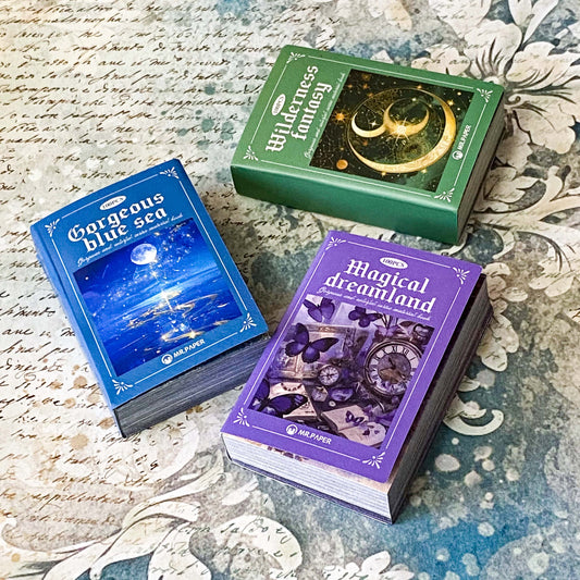 three mini scrapbook paper and vellum books in purple. lue and green themes with 100 sheets each for collage and journaling