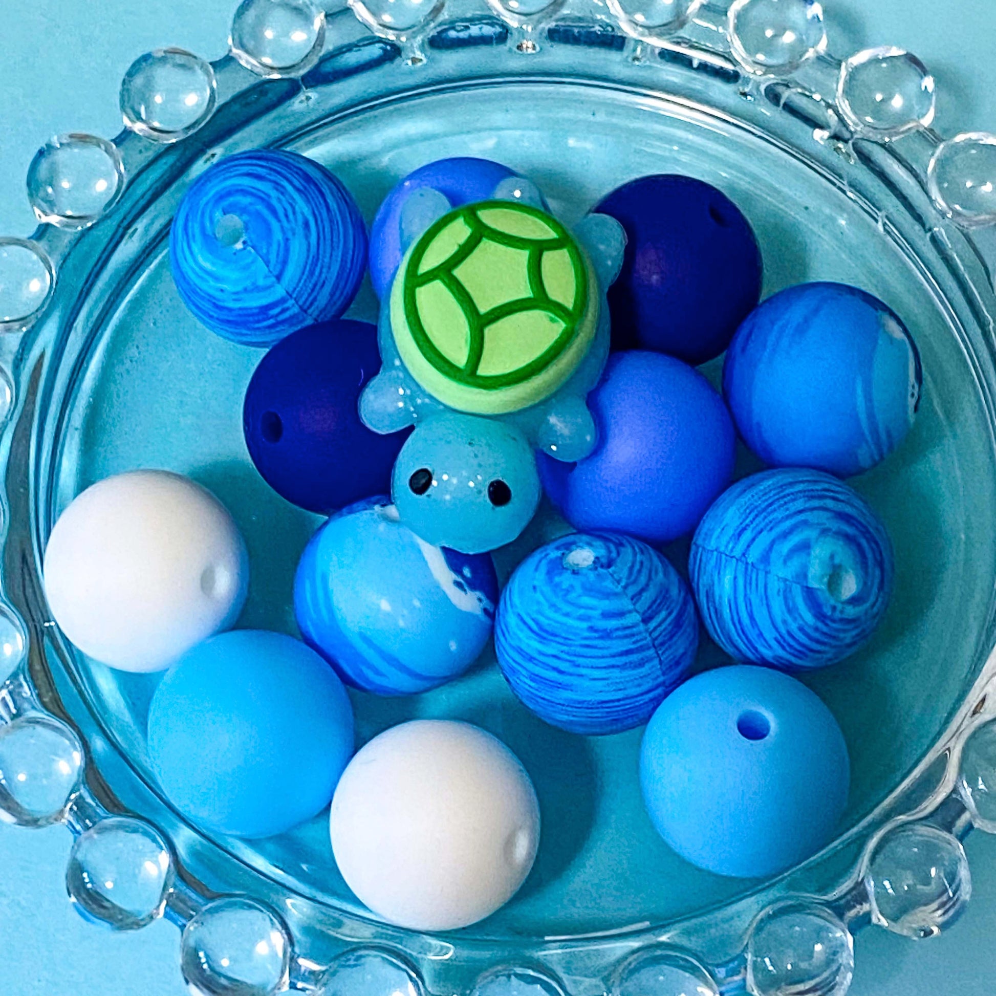 ocean turtle blue and green silicone beads bundle with glittery turtle focal bead and13 other round 16mm beads in blue, aqua, white and patterned.