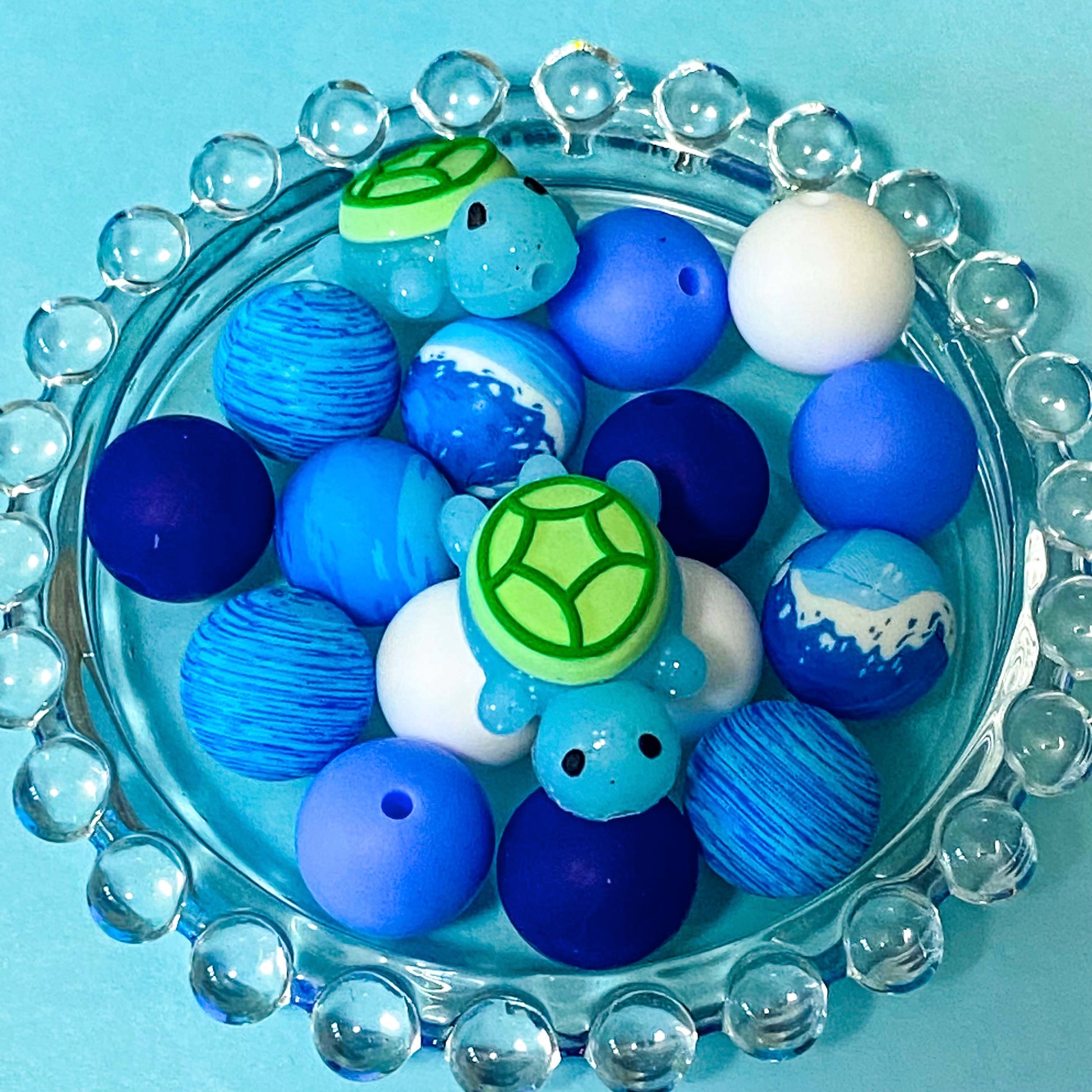 ocean turtle blue and green silicone beads bundle with glittery turtle focal bead and13 other round 16mm beads in blue, aqua, white and patterned.