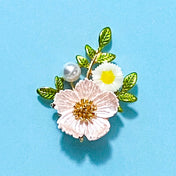 floral dog rose botanical enamel and metal gold brooch on a blue background