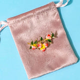 branch of peach fruits brooch on a pink velvet pouch against a blue background