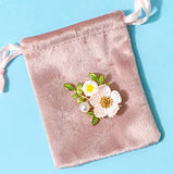 Pink velvet pouch with floral dog rose gold metal and enamel brooch on a blue background