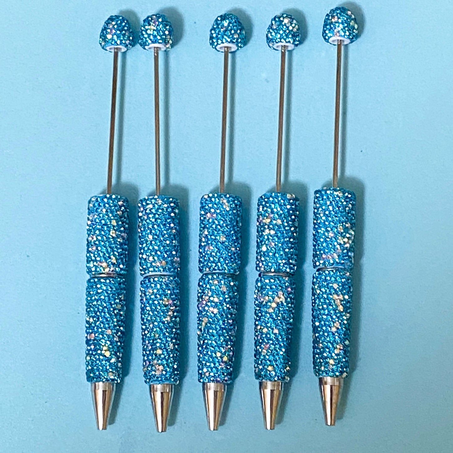 turquoise blue sparkly rhinestone decorative pen blanks with silver hardware on a blue background