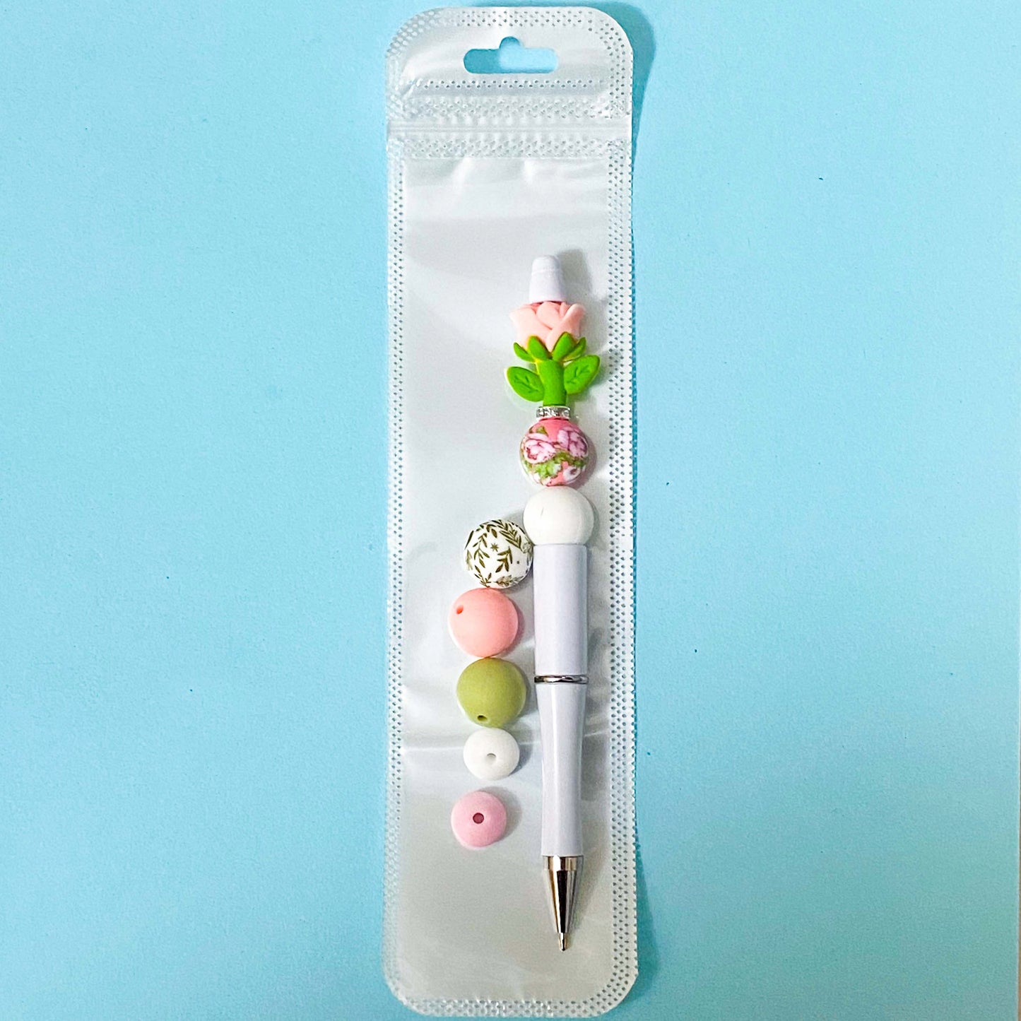 pink rose beaded pen spring diy kit in holo bag with extra beads on blue background