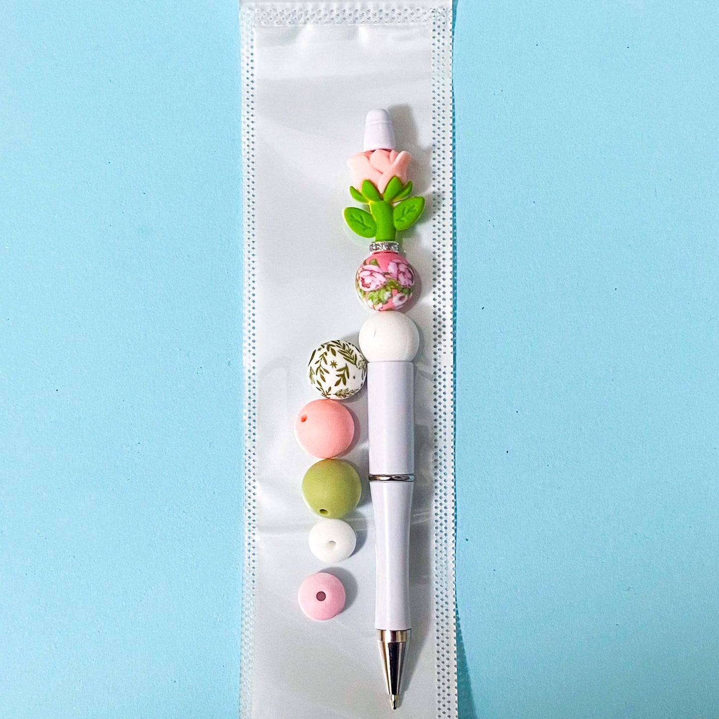 Decorative pen with colorful beads on a light blue background
