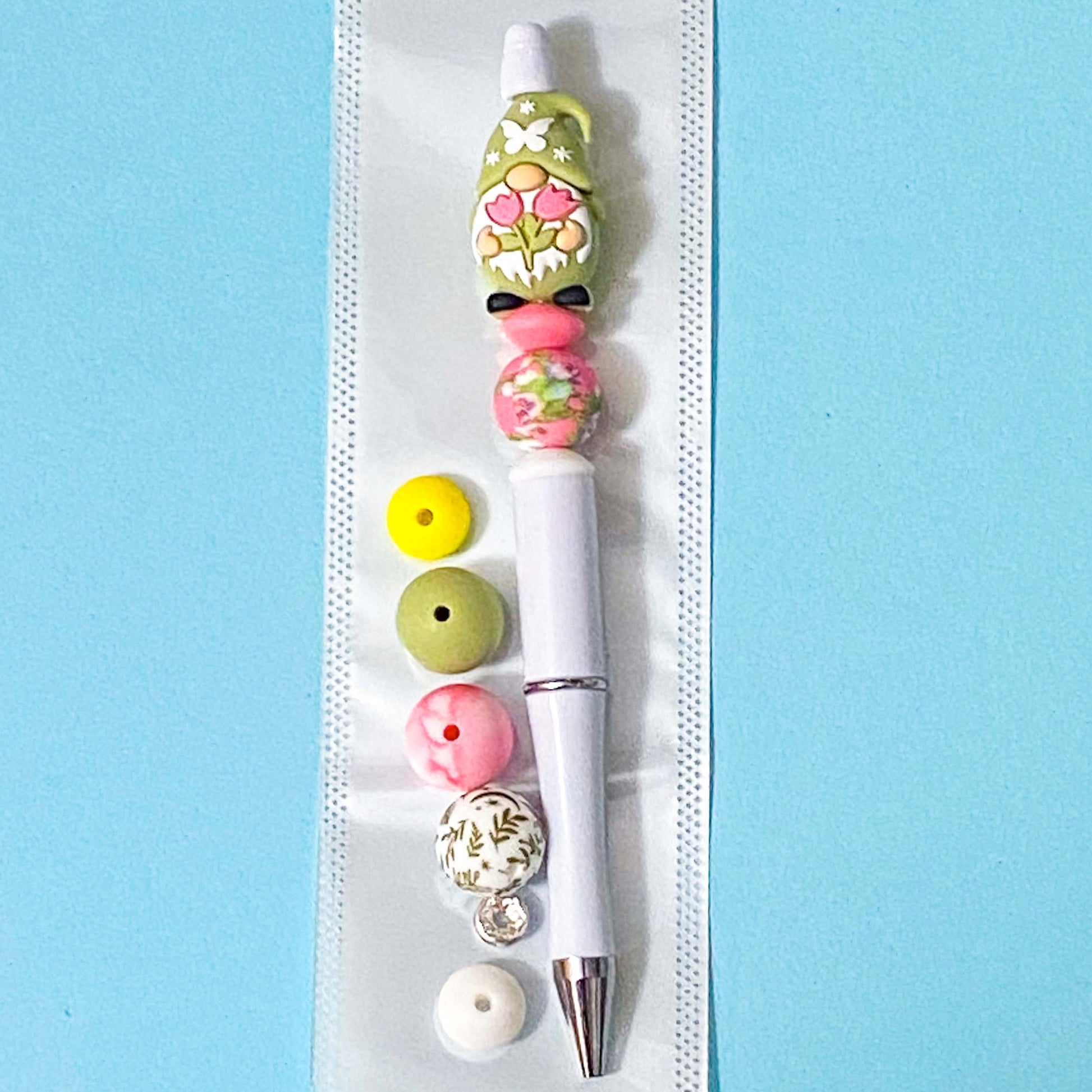 Decorative pen with colorful beads on a white strip against a blue background