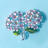 Floral hydrangea silver metal and enamel brooch with white and purple flowers on a blue background and sparkly rhinestones