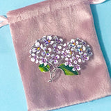 Floral hydrangea lilac and pink botanical brooch on a pink velvet bag on a blue background