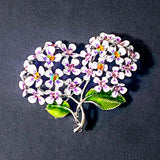 Floral hydrangea lilac and pink sparkly brooch with white flowers and green leaves on a dark background