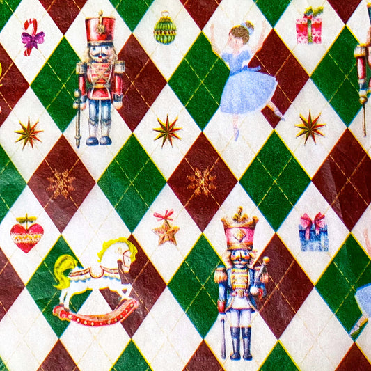 tissue paper with a pattern of nutcracker suite with Clara and rocking horse and tin soldier, on a dark red, green and cream argyle harlequin background.