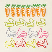 Colourful spring and easter metal jumbo paper clips shaped like carrots, ducks, and rabbits on a beige background