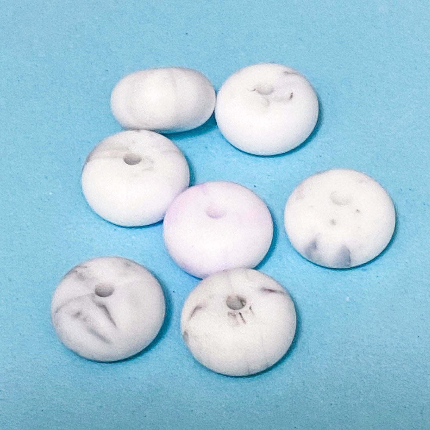 silicone spacer beads with a chunky shape in white marble on blue background