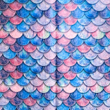 Pattern of blue, pink, and purple fish mermaid scales on sheets of tissue paper on a white background