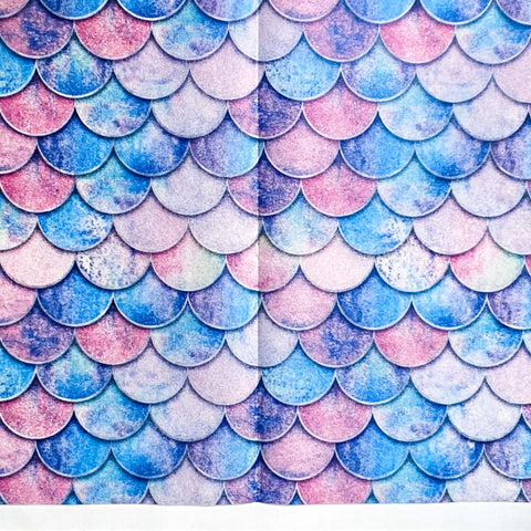 Pattern of blue, pink, and purple fish scales on sheets of tissue paper on a white background