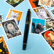 vintage cat stamp stickers spread on a blue background with a pen for scale, glossy decorative cat sticker set with multiple illustrated designs
