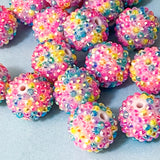 glittery large beads with a multicolour rainbow pattern on a blue background