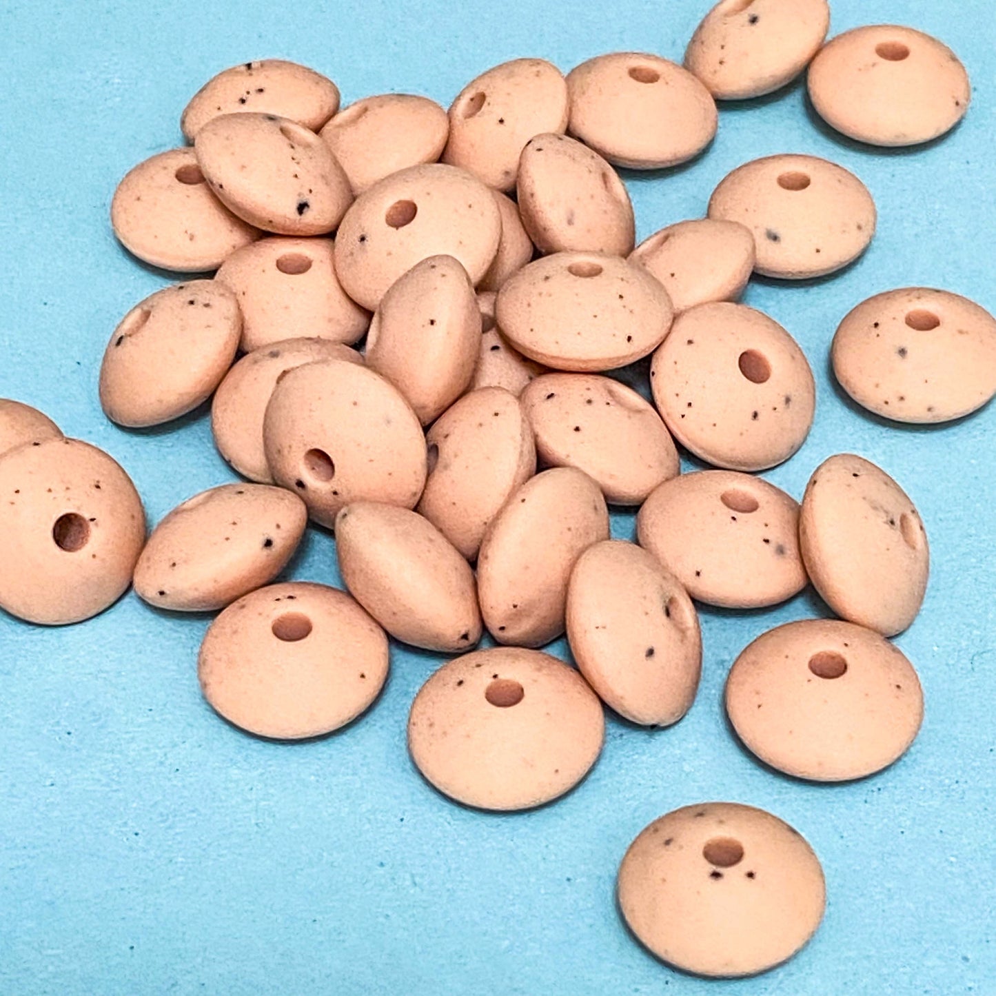 pastel peach speckle pattern silicone beads on a blue background