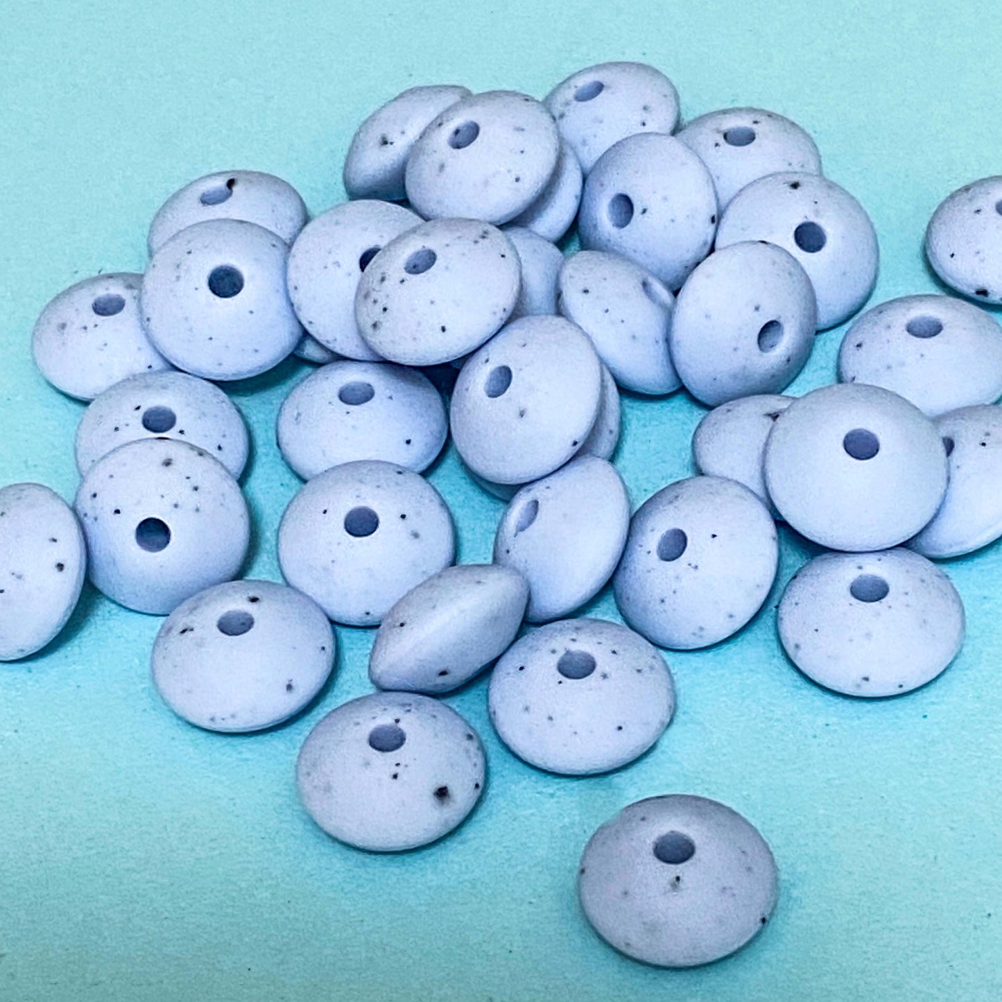pastel blue speckle pattern silicone spacer beads on a blue background