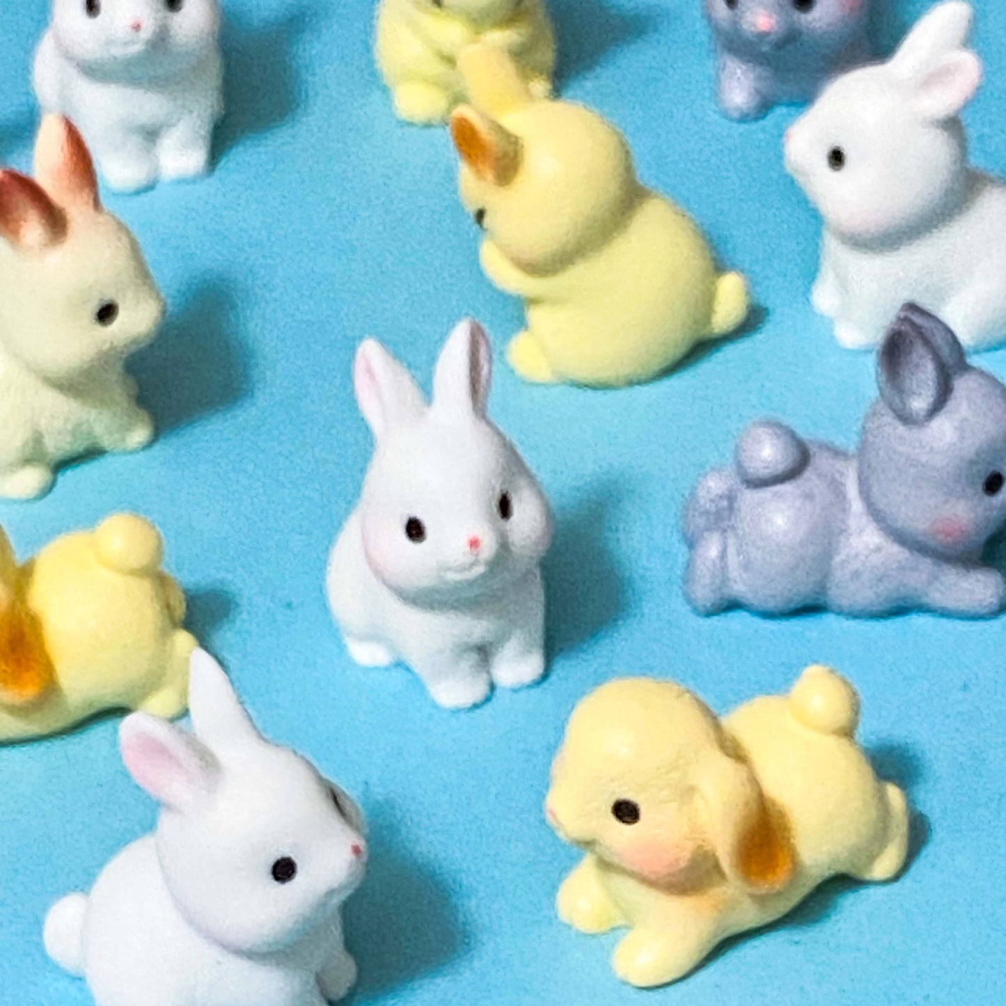 Set of small rabbit resin 3D figurines in various colours on a blue background