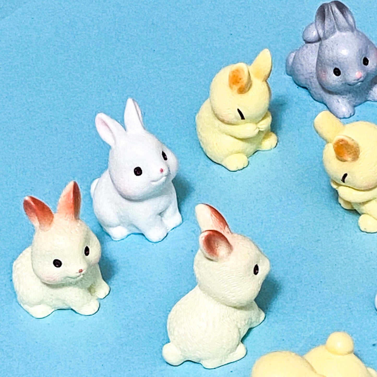Set of small rabbit resin 3D figurines in various colours on a blue background