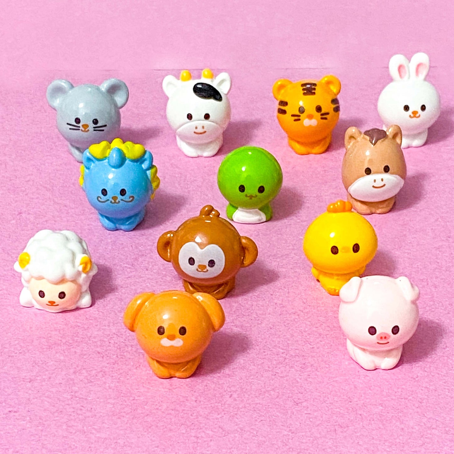 year of the Chinese zodiac animal miniature figurines on a pink background