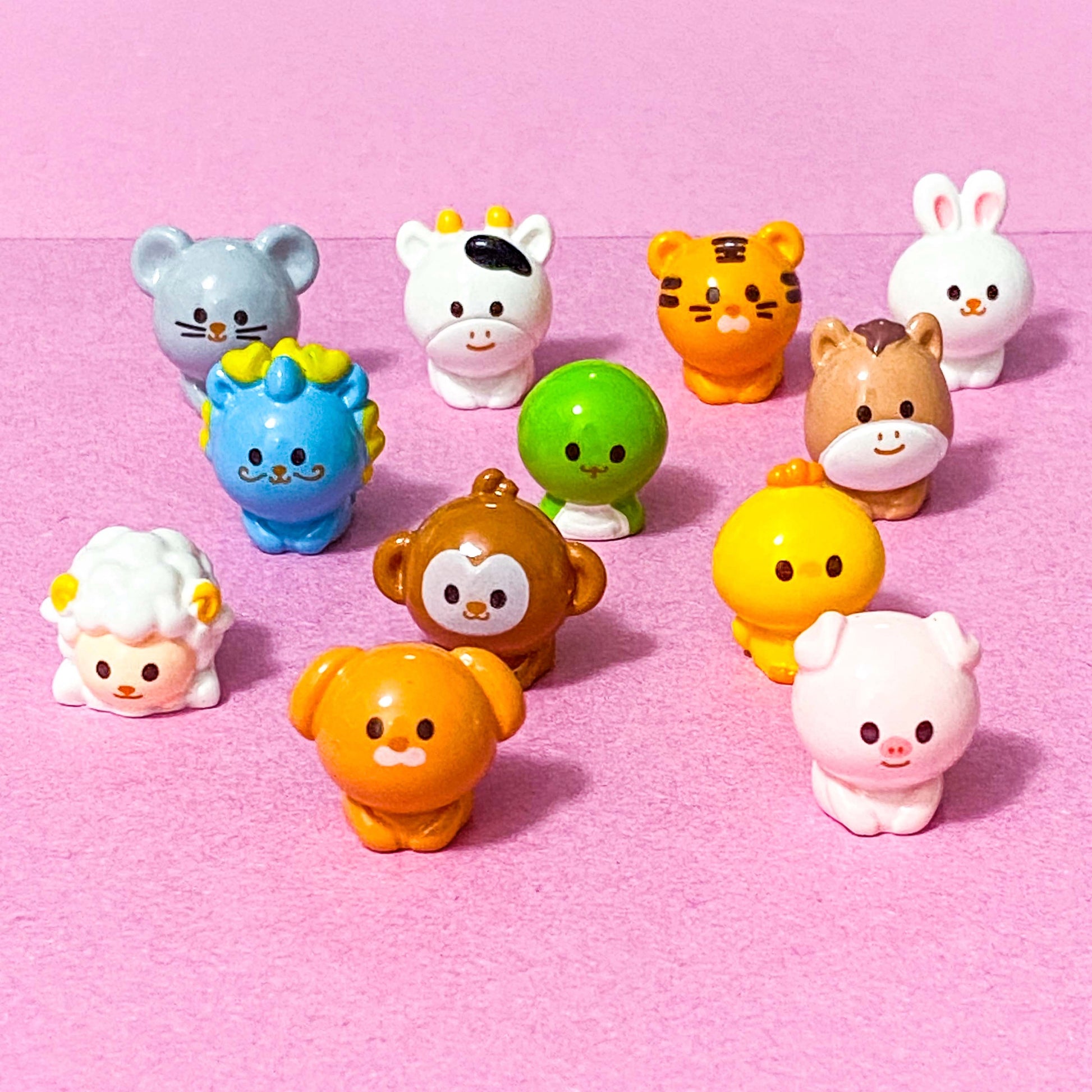 chinese zodiac animal miniature resin figurines on pink background