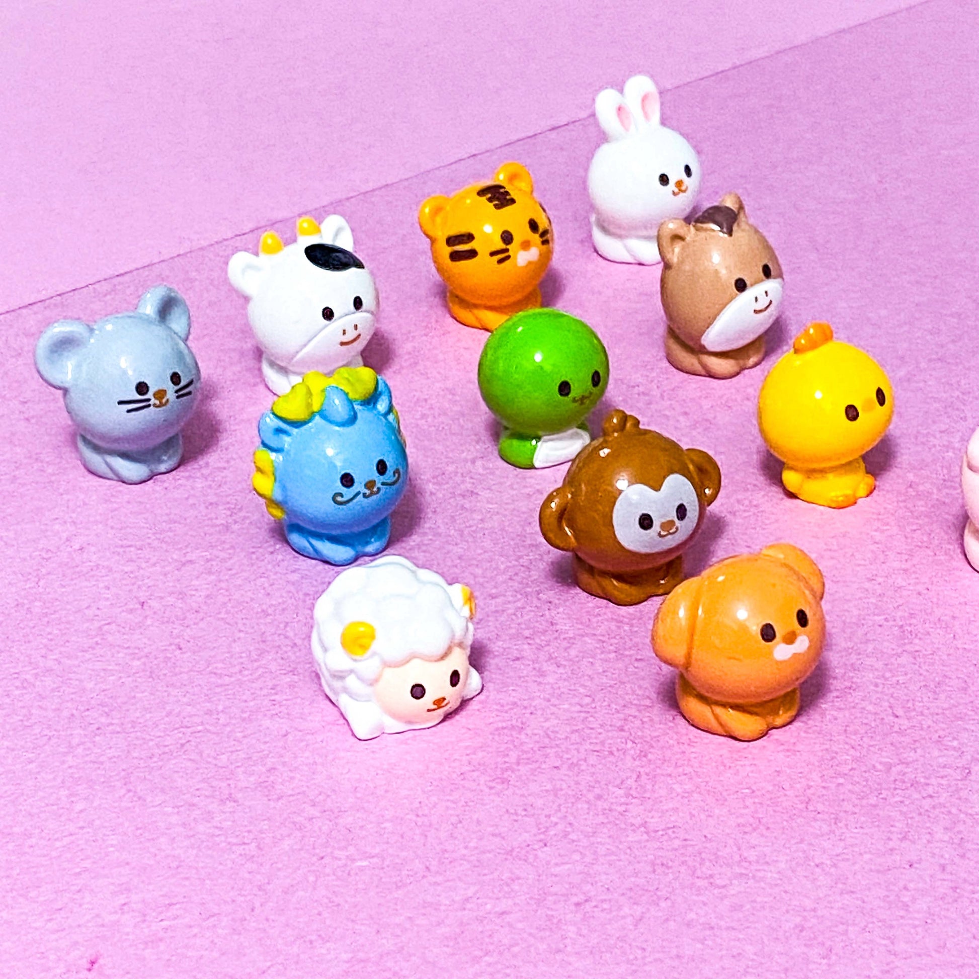 Chinese zodiac animal miniature figurines on a pink background
