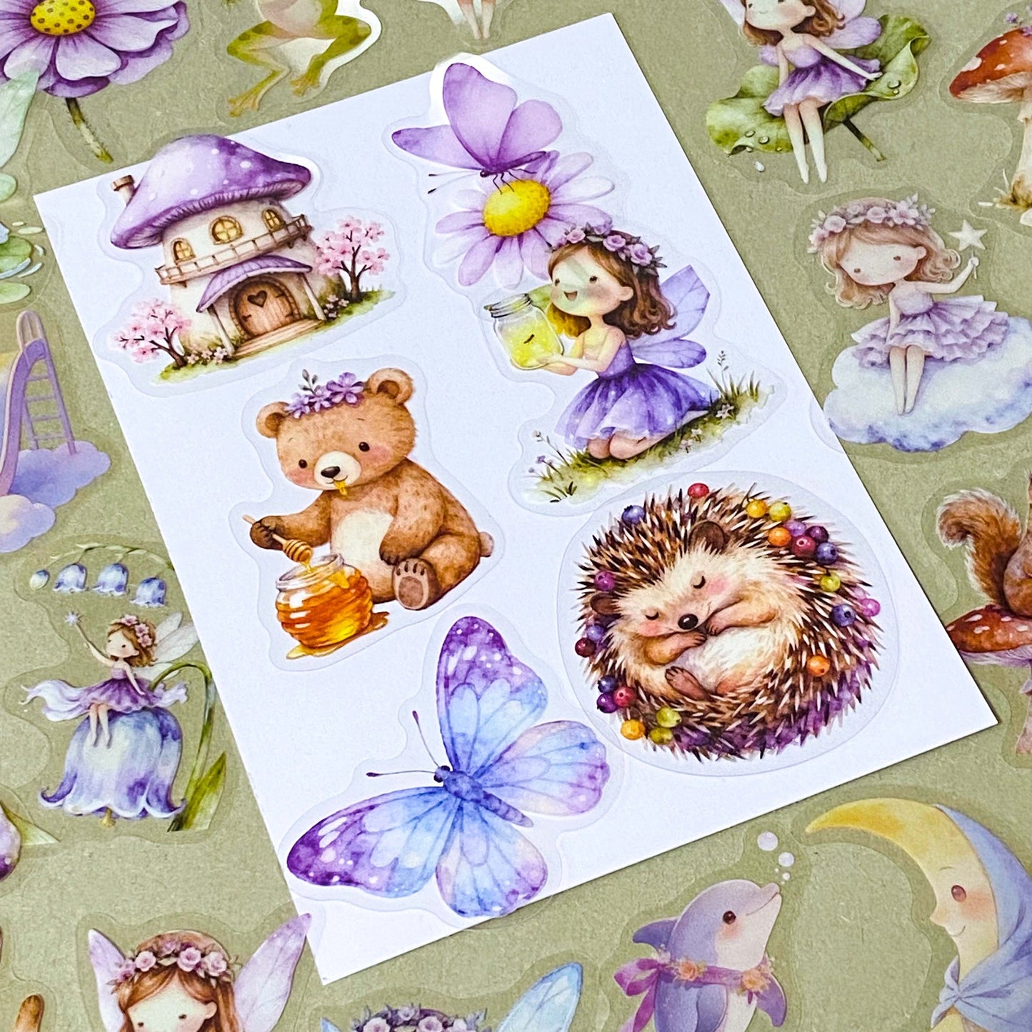 collection of 50 different pastel storybook stickers featuring fairies, woodland animals, flowers, castles, moons and butterflies and enchanted cottagecore illustrations in soft lilac and lavender tones.