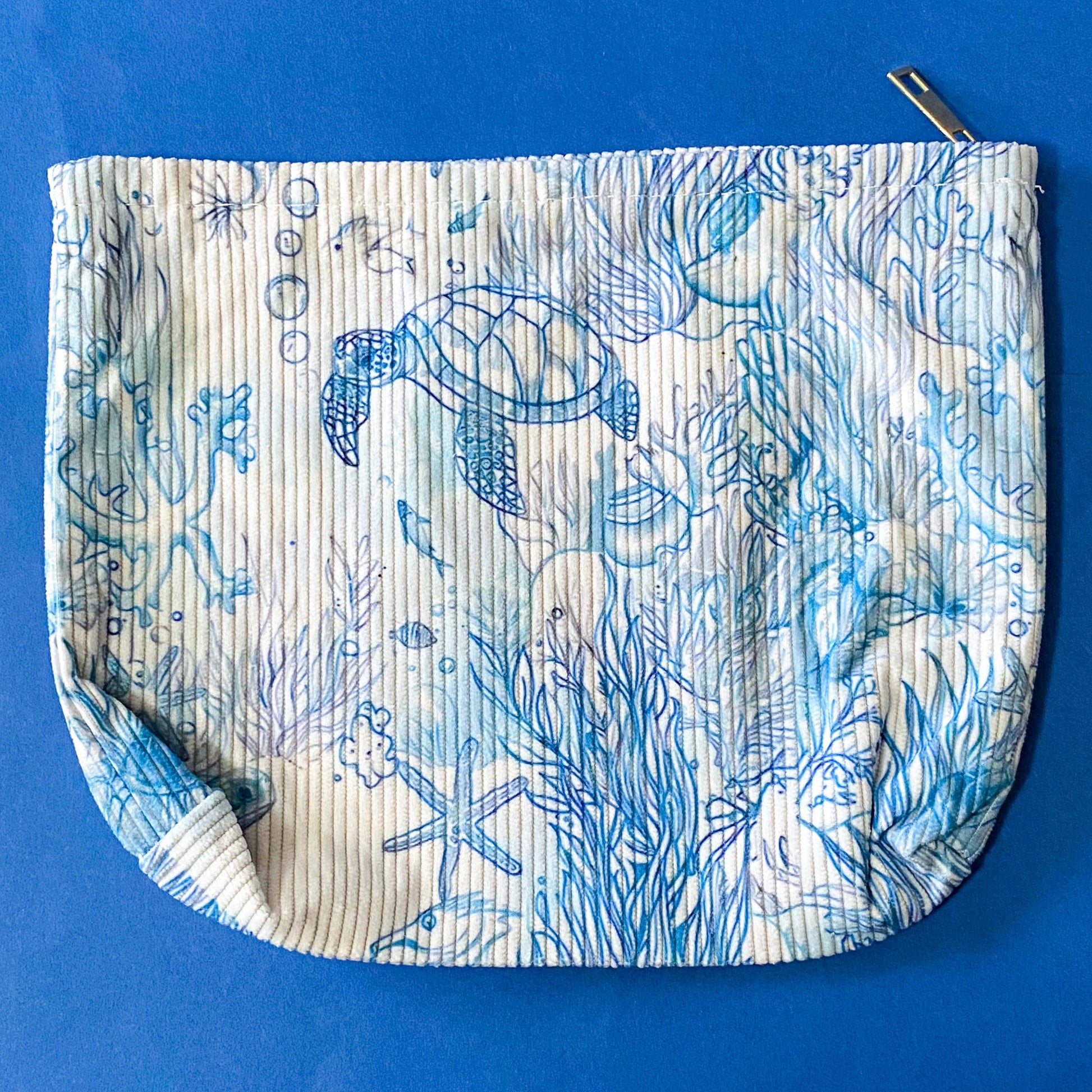 white and pale blue corduroy zip pouch with an underwater illustration featuring sea turtles, fish, marine plants. It is fully lined with waterproof fabric and finished with a sturdy metal zip. uk letterbox gift shop.