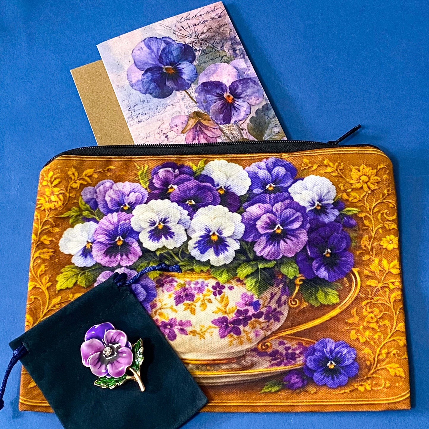 golden floral fabric pouch featuring purple and white pansies in a vintage teacup with matching enamel and metal rhinestone brooch in velvet gift bag and coordinating pansy greeting card with kraft envelope.